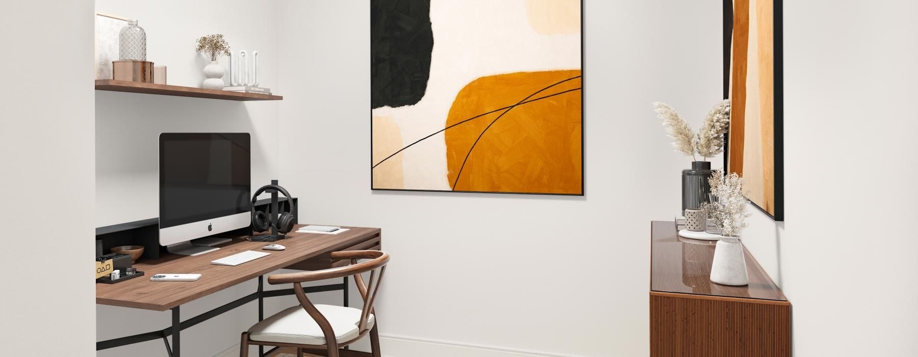 a desk with a computer and a chair in a room with a wall with art on it
